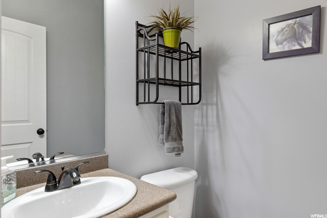 Half bathroom with toilet, mirror, and vanity