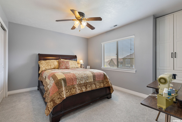 Carpeted bedroom featuring natural light and a ceiling fan