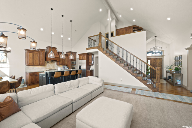 Living room with a breakfast bar area, hardwood floors, a high ceiling, and lofted ceiling