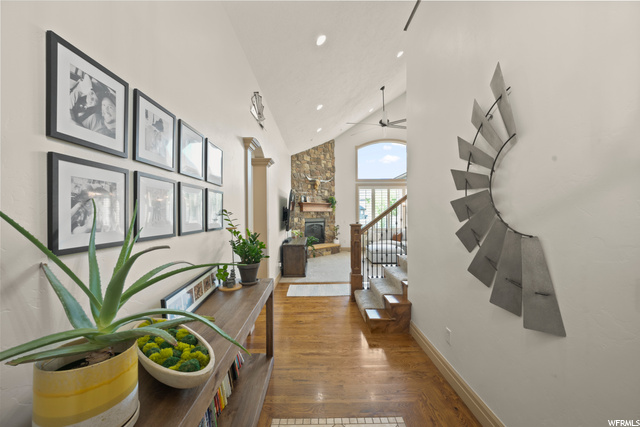 Corridor featuring a high ceiling, natural light, lofted ceiling, and hardwood flooring