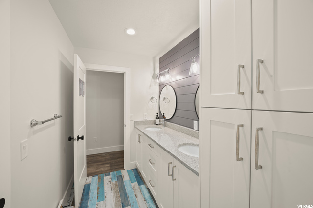 Bathroom featuring wood look tile flooring, mirror, and double vanity