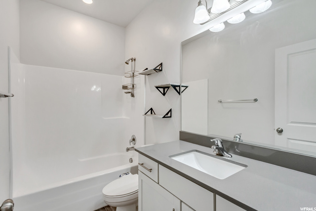 Full bathroom with vanity, mirror, shower / bathtub combination, and toilet
