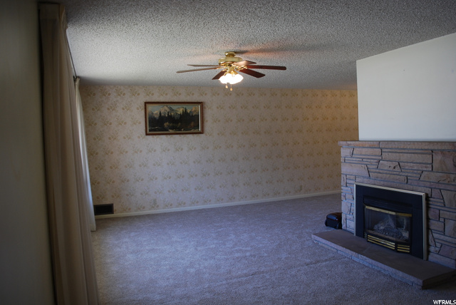 Carpeted living room featuring a fireplace and a ceiling fan