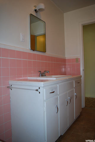Bathroom featuring tile flooring, vanity with extensive cabinet space, and multiple mirrors