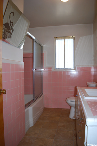 Full bathroom with tile flooring, vanity, bath / shower combo with glass door, and toilet