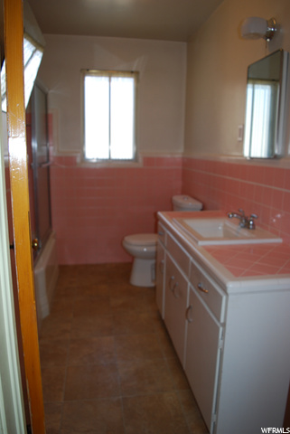 Half bathroom featuring tile flooring, natural light, mirror, toilet, and vanity