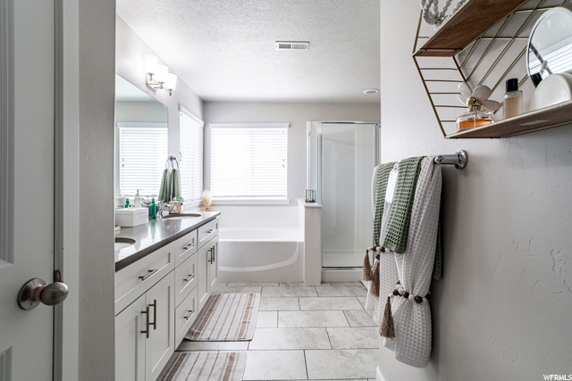Bathroom with tile floors, natural light, mirror, separate shower and tub enclosures, and his and hers vanity
