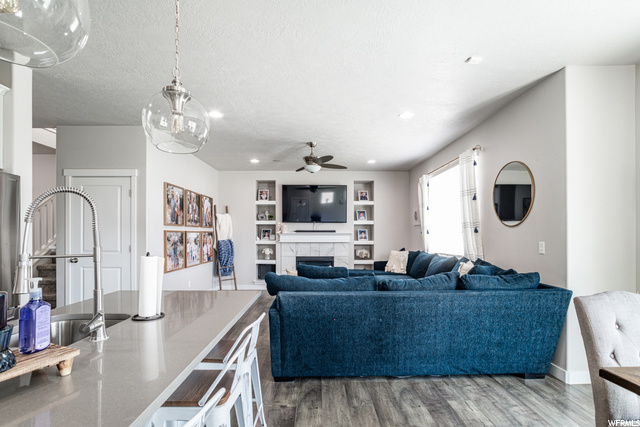 Living room featuring a fireplace, natural light, a ceiling fan, hardwood flooring, and TV