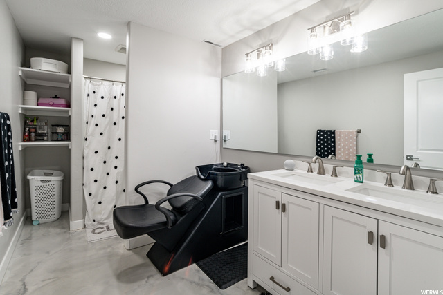 Bathroom featuring tile floors, dual vanity, shower curtain, and multiple mirrors