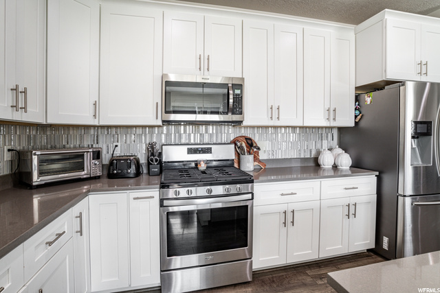 Kitchen featuring gas range oven, microwave, white cabinets, and dark floors