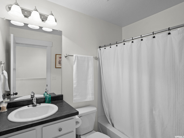 Full bathroom with oversized vanity, mirror, and shower / bathtub combination with curtain