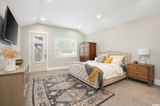 Bedroom featuring light carpet and lofted ceiling