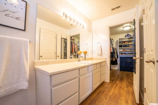 Bathroom with vanity with extensive cabinet space, mirror, and light hardwood floors