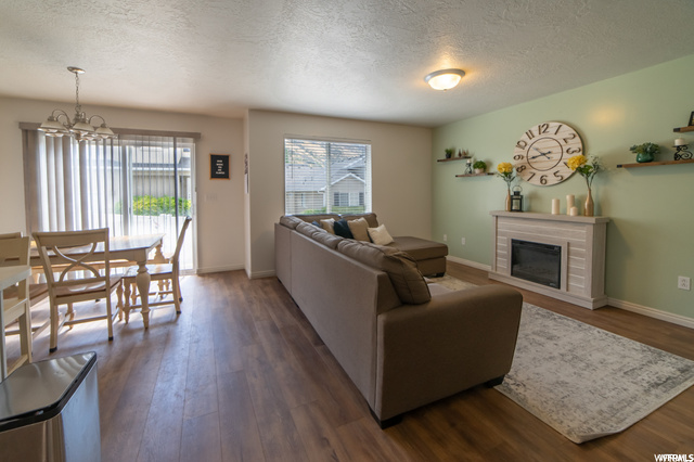 Living room featuring a textured ceiling, a fireplace, and light hardwood flooring