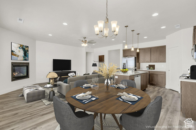 Dining room with sink, ceiling fan with notable chandelier, and light hardwood / wood-style floors