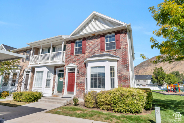 View of front of house with a front yard and a balcony