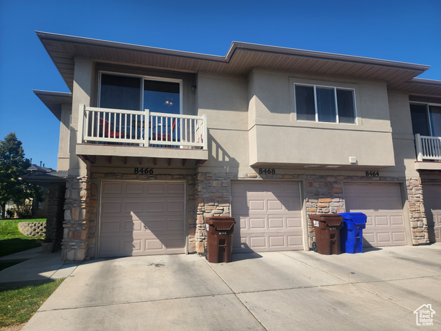 View of front of home featuring a garage and a balcony