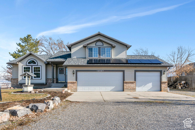 View of front of property featuring solar panels and a garage