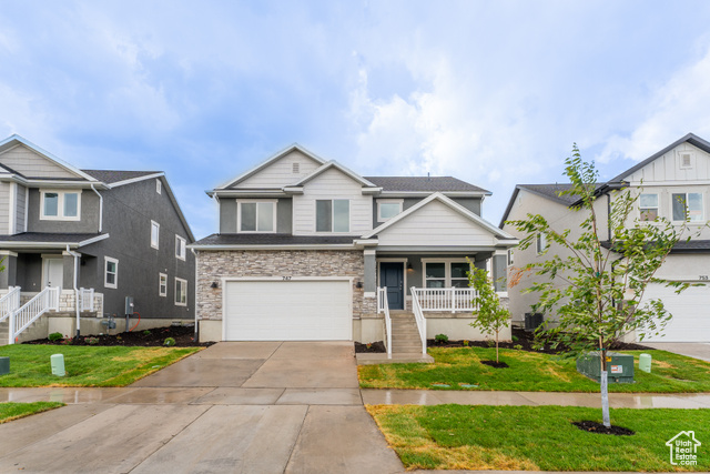 View of front of house featuring a front lawn, covered porch, and a garage