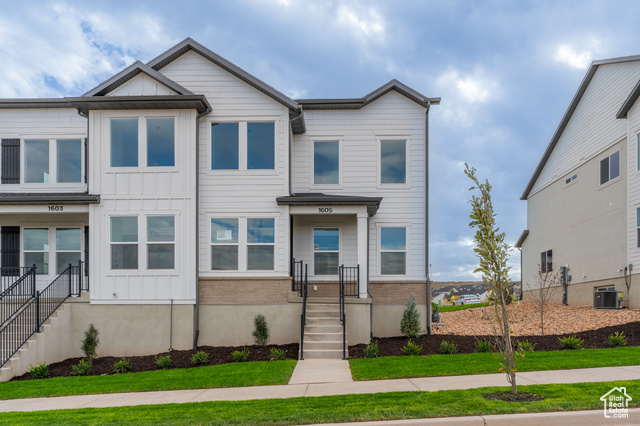 View of front of home with central AC unit and a front lawn