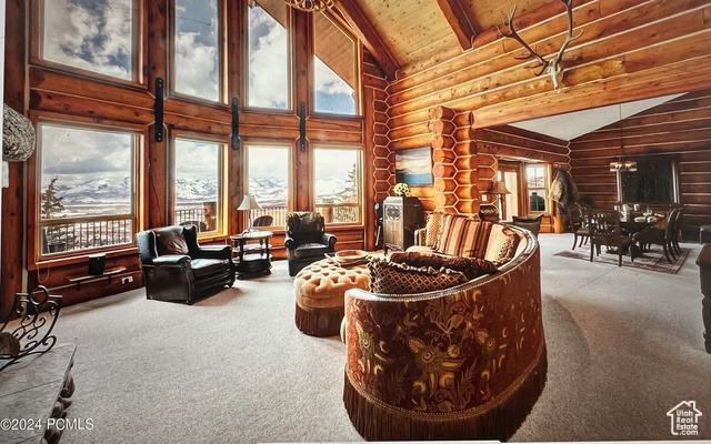 Carpeted living room with high vaulted ceiling, rustic walls, beam ceiling, and wood ceiling
