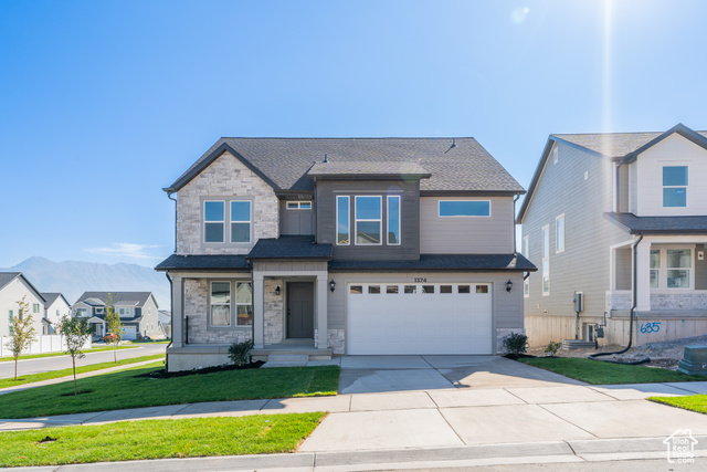 View of front of home with a garage, a mountain view, and a front lawn