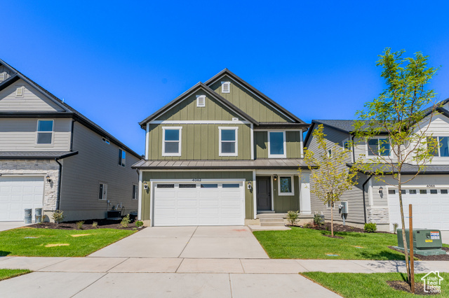 View of front of home featuring cooling unit, a front yard, and a garage