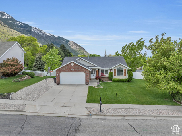 Single story home featuring a mountain view, a garage, and a front lawn