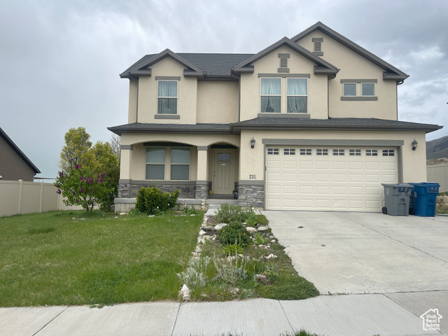 View of front of home with a garage and a front lawn