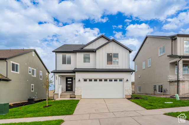 View of front of home with a garage, central AC unit, and a front yard