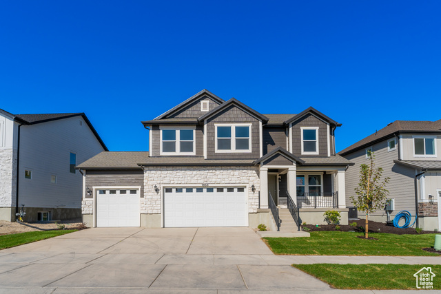 View of front of house featuring a porch, a front yard, and a garage