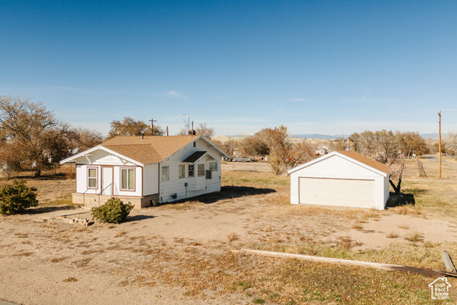 View of side of home featuring a rural view, an outdoor structure, and a garage