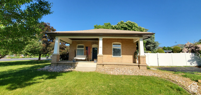 Bungalow-style home with a front yard and covered porch