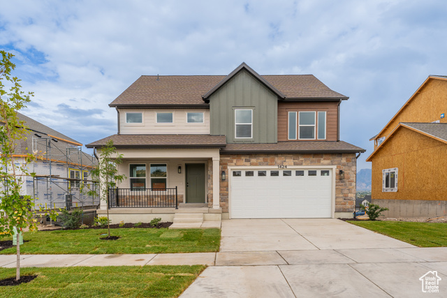 View of front of property with a garage, a front lawn, and covered porch