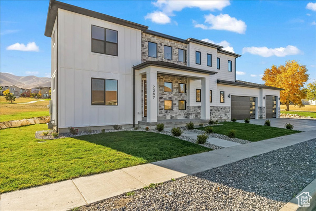 View of front of home with a front lawn, a garage, and a mountain view