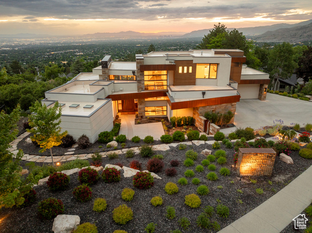 Magnificent modern home designed to blend into its amazing natural setting. Stone, glass, copper and wood accents combine with a magical effect. Wide expanses of glass plus extensive clerestory windows are perfectly placed to capture 360 of incredible city, mountain and sunset views. There is no better view position, or location, in the valley.  Everything here is custom with beauty, livability and lasting quality all in one. A tranquil courtyard entry leads to the artistic modern wood entry door and luxe double height "great room" with breathtaking views framed. Fabulous open kitchen and elegant dining are accessorized with creative finishes and flow via seamless pocket glass to the expansive "living deck" with fire, views, cooking facilities and a stone pizza oven! Complete main floor living includes a very spacious primary suite with luxurious sleep, bath and dressing spaces lined with the ultimate finishes possible. Laundry is on the main. Two enticing guest suites are up, placed next to a den area with access to more amazing outdoor space. The daylight lower level has an exceptional rec area, built-ins and fireplace plus a fabulous theatre, two more deluxe guest suites and an easy flow out to nature. Patios, decks and ambiance day and night are at one with the interiors. The stainless and wood staircase rises against a stone wall, which ties into other stone and metals in view. Special lighting details are throughout. An elevator is preplanned to access all floors, if desired. Exquisite fireplaces, ceiling details, built-ins and art display enhance. Equipped with smart home technology. The landscaping is second to none, and the garage is an oversized four with heat!   An exquisite showplace for entertaining and leisure living.  This is the ultimate!