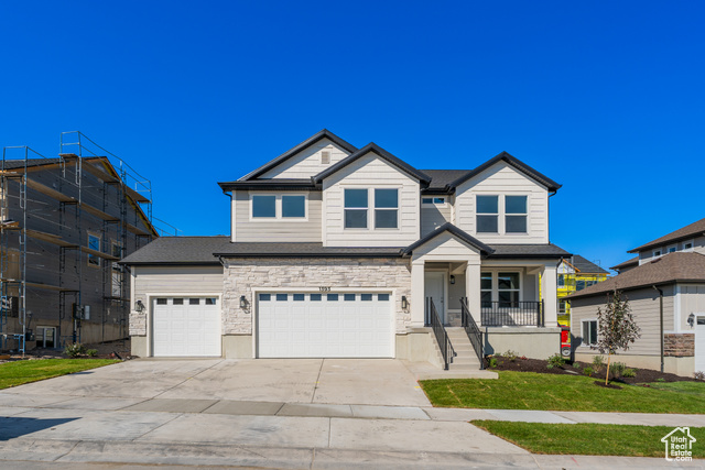 View of front of property featuring a porch, a front yard, and a garage