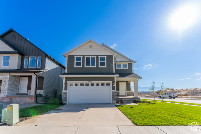 View of front of property with covered porch, a front yard, and a garage