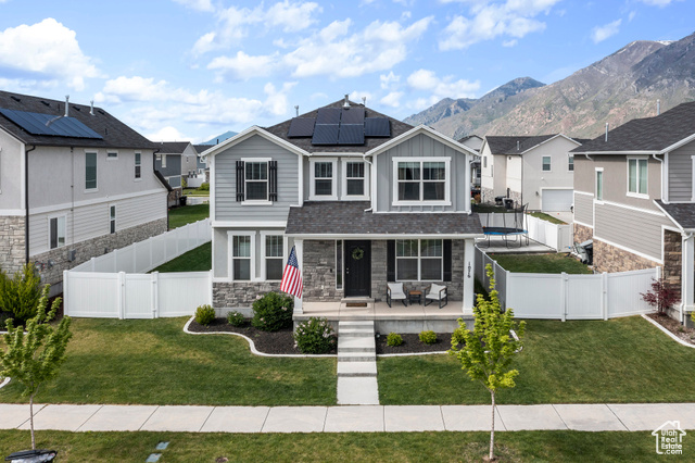 View of front of property with a front yard, a mountain view, and solar panels