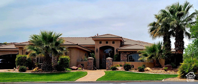 Mediterranean style house featuring mature landscaping, courtyard entrance and front lawn.