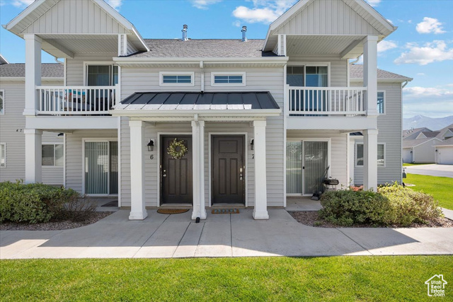 View of front facade with a garage, a front lawn, and a balcony