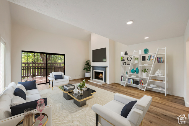 Living room with a towering ceiling and light hardwood / wood-style flooring