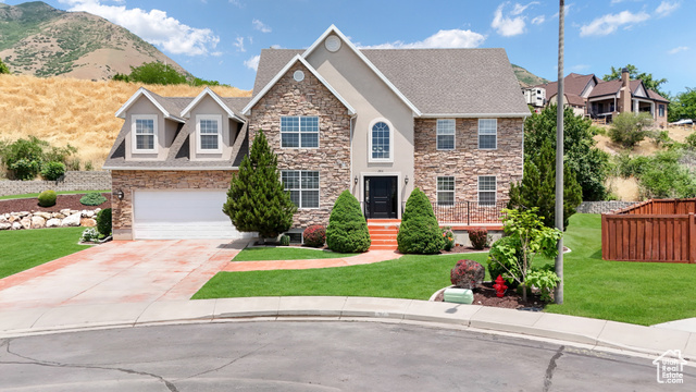 View of front of property featuring a mountain view, a front yard, and a garage