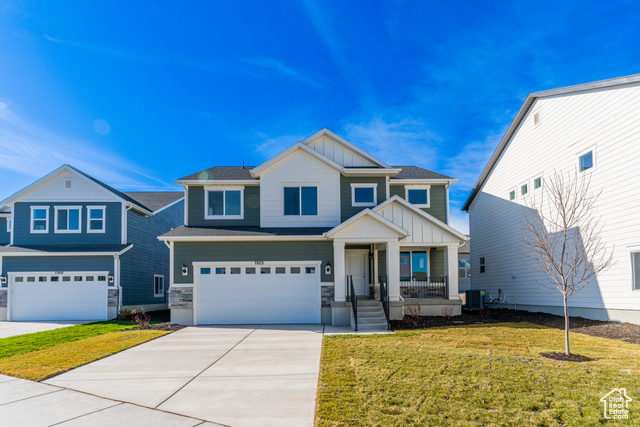 Craftsman house with covered porch, a front lawn, a garage, and cooling unit