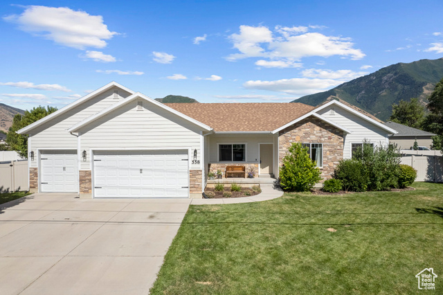 View of front of property featuring a mountain view, a garage, and a front yard