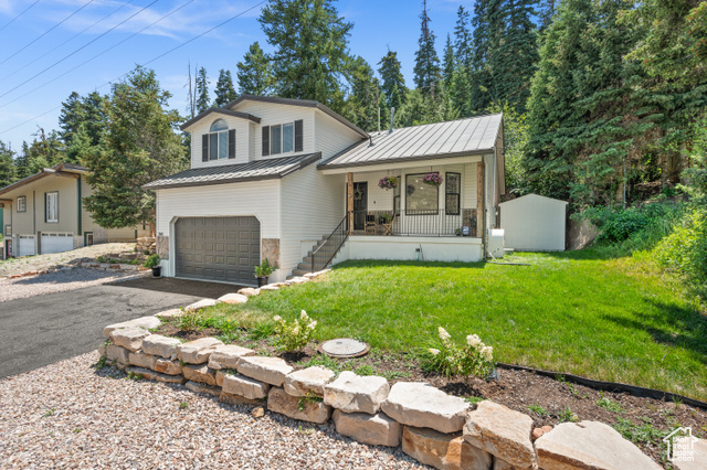 View of front of house featuring covered porch, a garage, and a front lawn