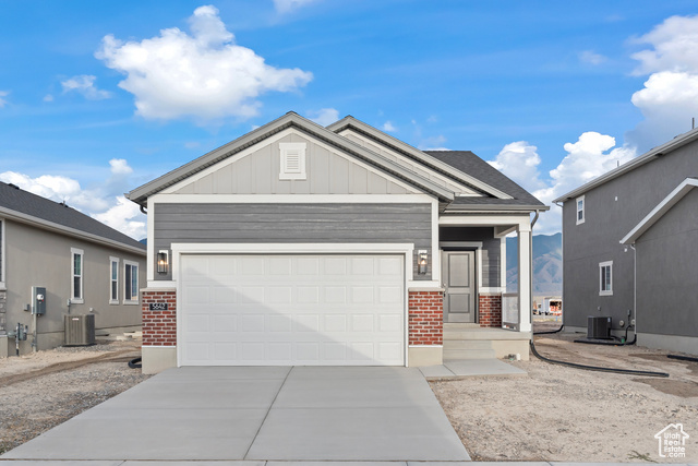 View of front of home with a garage and central air condition unit