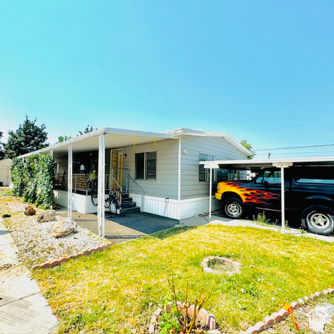 View of front of property featuring a carport and a front lawn