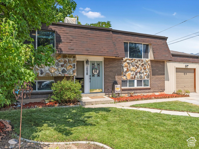 View of front of property with a garage and a front lawn