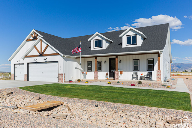 View of front facade with a garage, covered porch, and a front lawn